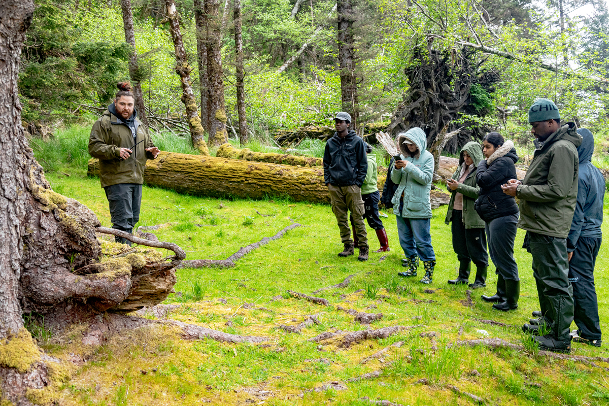 The guide at K'uuna tells students about one of the carvings.