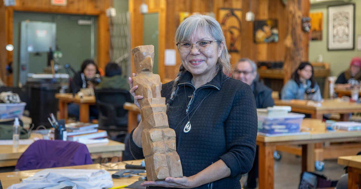 Lou Ann Neel holds the totem pole her grandmother carved