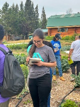 A student takes notes as they explore a field of crops.